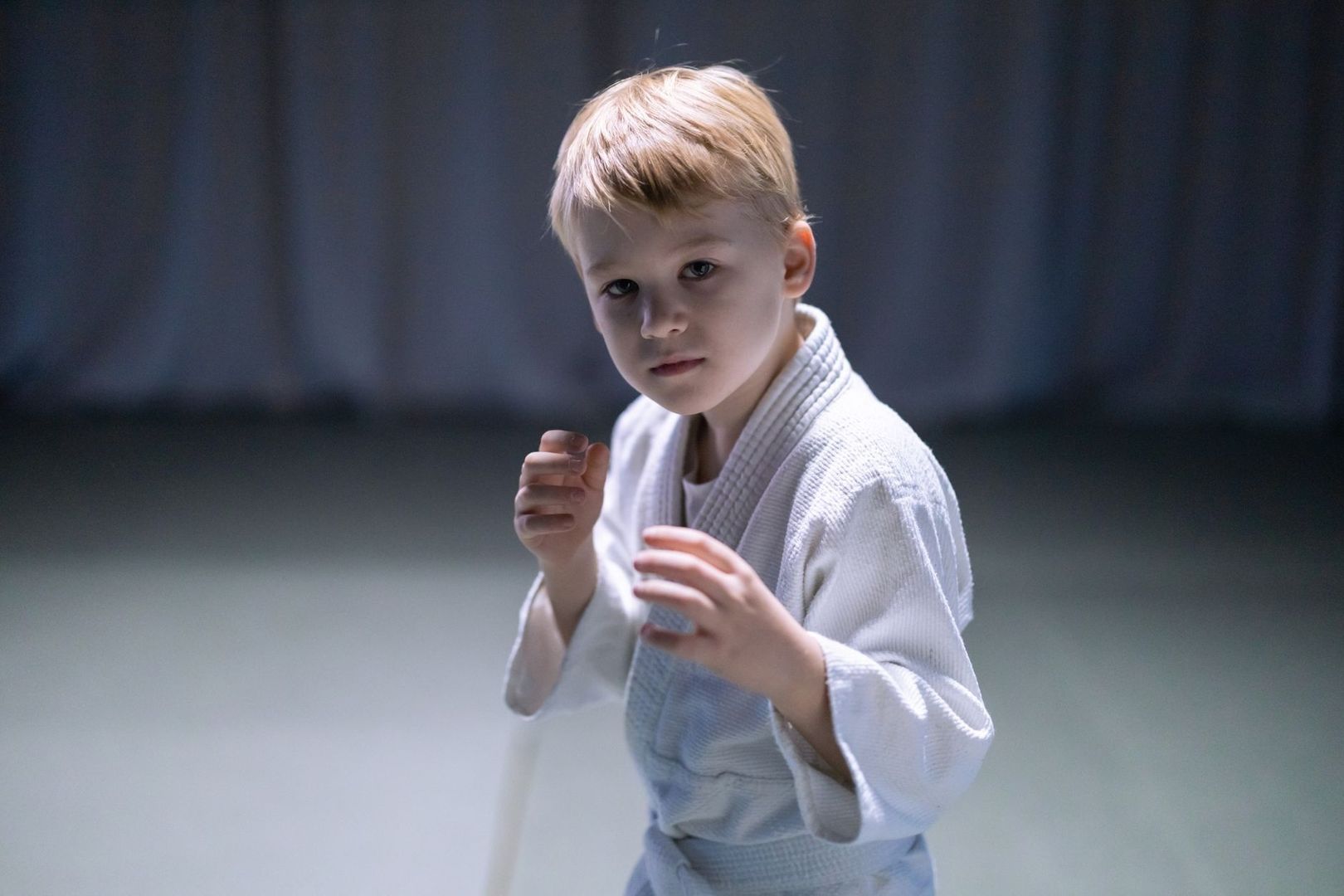 Young child in a white martial arts uniform practicing a guarded stance